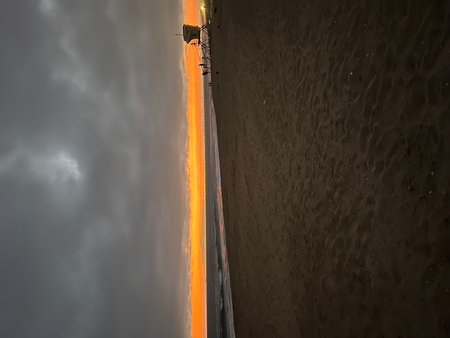 Serene Beach Sunset Glow Illuminating the Horizon as Waves Gently Crash on the Shoreの写真素材