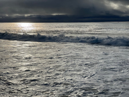 Serene Waves Dance Under a Moody Sky at the Ocean's Edge During Twilightの写真素材