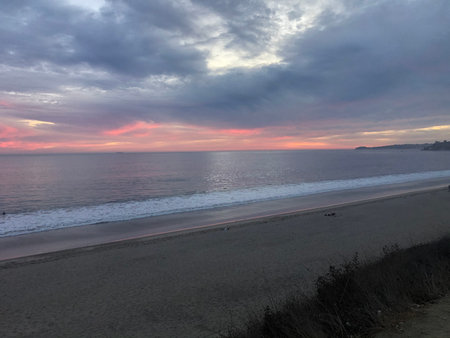 Calm Evening by the Beach With Pastel Skies and Gentle Waves at Sunset Near the Shoreの写真素材