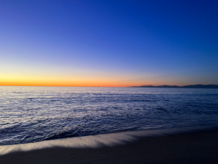 Captivating Sunset Over the Calm Ocean Creates a Serene Atmosphere Along a Peaceful Shorelineの写真素材