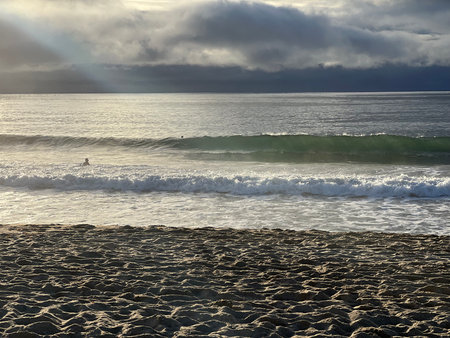Surfing on a Tranquil Morning at the Beach Under a Cloudy Sky With Waves Gently Crashingの写真素材