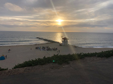 Gathering at Sunset on the Beach With Waves Gently Crashing and Clouds Casting a Warm Glowの写真素材