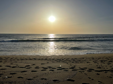 Sunset Casts Golden Light Over Gentle Waves on a Serene Beach in the Eveningの写真素材