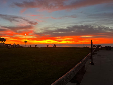 Stunning Sunset Over the Ocean With Silhouettes of People Enjoying the View at the Parkの写真素材