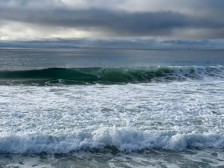 Waves Gently Crashing on a Serene Coastline Under an Overcast Sky During Early Morning Hoursの写真素材