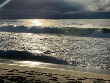 Gentle Waves Kiss the Sandy Shore as the Sun Sets Over the Tranquil Beach in the Late Afternoonの写真素材