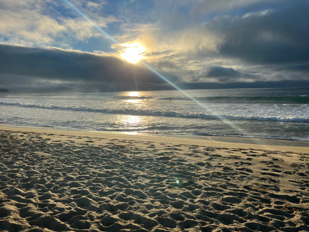 Majestic Sunset Over a Tranquil Beach With Soft Waves and Scattered Clouds Filling the Skyの写真素材
