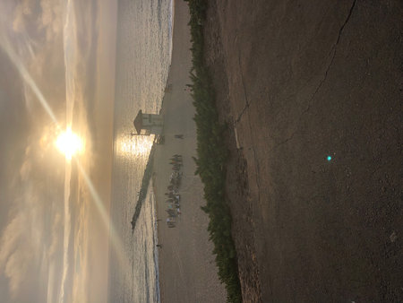 Sunset at the Beach With a Lifeguard Tower and People Gathering Along the Shoreの写真素材