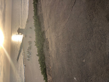 Sunset Casting Golden Rays Over a Tranquil Beach Gathering Near the Pier in Californiaの写真素材