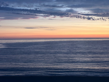 Breathtaking Sunset Over Calm Ocean Waters With Soft Pastel Colors Reflecting in the Skyの写真素材