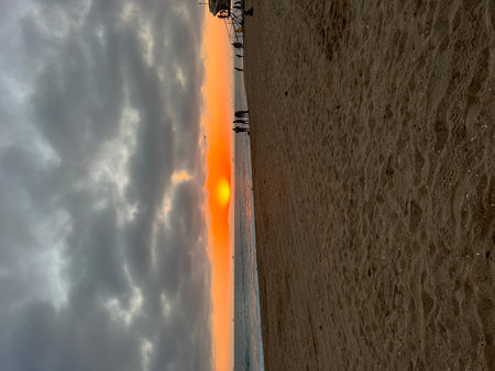 Majestic Sunset Over the Sandy Beach With Silhouettes of People Enjoying the Eveningの写真素材