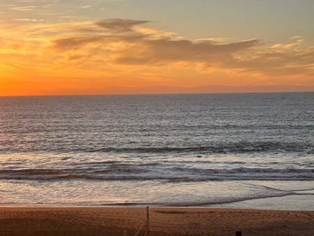 Vibrant Sunset Over the Ocean Creating a Serene Atmosphere at the Beachの写真素材