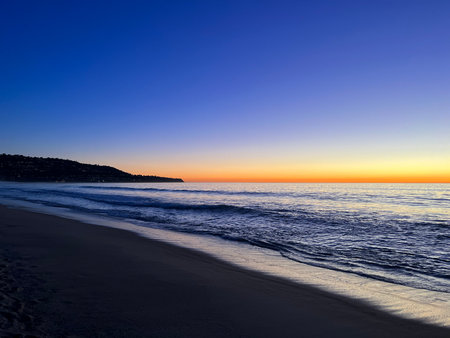 Majestic Sunset Over Calm Ocean Waves Along a Serene Beach at Dusk Generative AIの写真素材