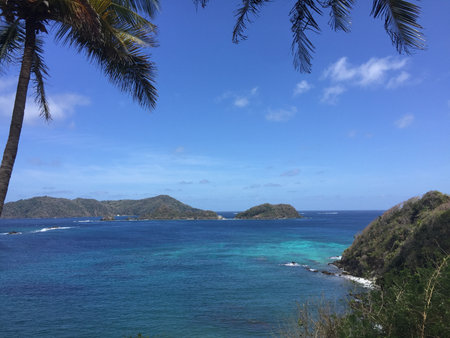 Serene Coastal View Revealing Turquoise Waters and Green Hills Under a Clear Sky in a Tropical Paradiseの写真素材