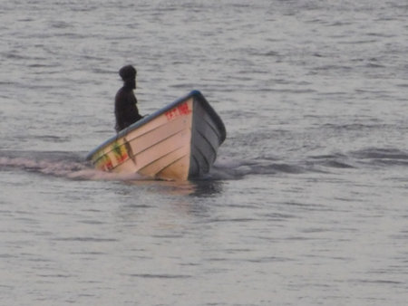 Sunset Fishing Trip on Calm Waters With a Lone Figure in a Small Boat Navigating Quietlyの写真素材