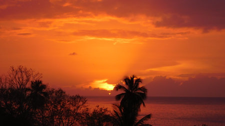 Stunning Sunset Over the Ocean With Vibrant Orange and Purple Hues Shining Through the Cloudsの写真素材