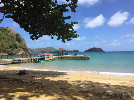 Relaxing Beach Scene With a Colorful Boat Docked by the Shoreline on a Sunny Day in a Tropical Paradiseの写真素材