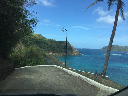 Scenic Coastal Drive Along the Turquoise Waters and Lush Hills of a Tropical Paradiseの写真素材