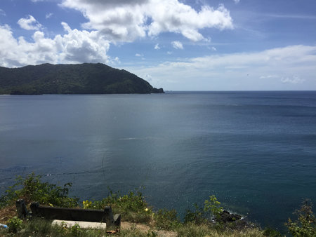 Serene Coastal View With Gentle Waves and Distant Mountains Under a Bright Blue Skyの写真素材