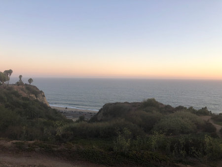 Sunset Glow Over the Serene Coastline With Gentle Waves Lapping at the Shore and a Tranquil Atmosphereの写真素材