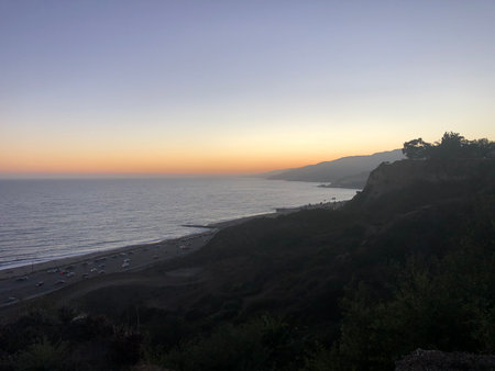 Sunset Over the Tranquil Coastline With Waves Gently Crashing on the Shore at Duskの写真素材