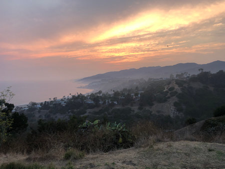 Sunset View Over the Tranquil Coastline and Hills of a Serene Landscape During Twilightの写真素材