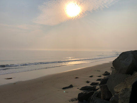Sunset Over the Tranquil Beach With Smooth Waves Reflecting Golden Sunlight in a Serene Coastal Settingの写真素材
