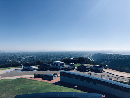 Scenic Overlook Captures Vehicles Parked at a Viewpoint on a Sunny Day, With a Vast Landscape in the Background Revealing City and Natureの写真素材