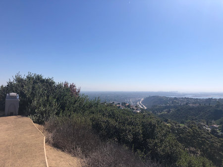 Breathtaking Panorama of Rolling Hills and Distant Cityscape in Bright Sunlightの写真素材