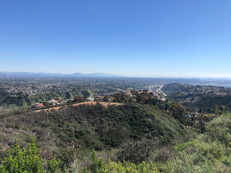 Expansive View of a Sunny Valley Surrounded by Mountains and Distant City Skyline in Californiaの写真素材
