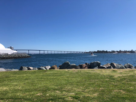 Scenic Waterfront View Featuring a Bridge and Calm Waters on a Sunny Dayの写真素材
