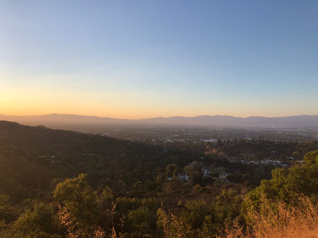 Breathtaking Sunset Over a Valley With Distant Mountains and City Lights in the Horizonの写真素材