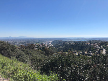 Vast Green Hills Meet the Sprawling Cityscape Under a Clear Blue Sky in This Serene Landscape Viewの写真素材