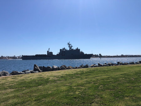 Majestic Naval Vessel Sails Through Calm Waters Under a Clear Blue Sky Near the Shoreline Parkの写真素材