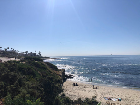 Sunny Day at the Beach With Gentle Waves and People Enjoying the View on the Coastlineの写真素材