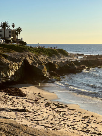 Sunset Glow Illuminates Coastal Cliffs and Serene Waves by the Beach at La Jolla in Californiaの写真素材