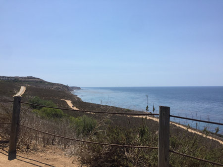 Scenic Coastal View From a Hiking Trail Overlooking the Ocean and Distant Cliffs on a Sunny Dayの写真素材