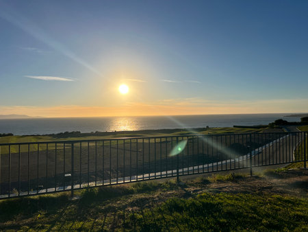 Sunset Over the Ocean Creates a Serene Atmosphere Near the Coastal Fence During a Peaceful Eveningの写真素材