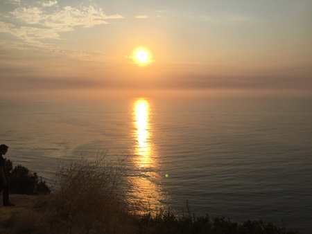 Captivating Sunset Over the Serene Ocean With a Silhouette of a Person Enjoying Nature's Beautyの写真素材
