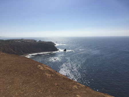 Sunlight Dances on Ocean Waves Along the Rugged Coastline Overlooking Cliffs and Rocky Outcropsの写真素材