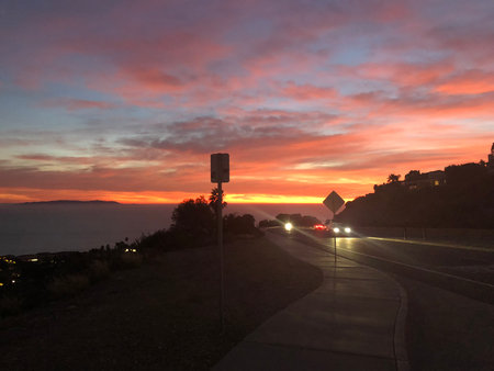 Vibrant Sunset Paints the Sky Over a Coastal Road by the Oceanの写真素材