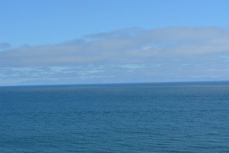 Calm Ocean Waves Meet a Clear Blue Sky in the Serene Coastal Landscape by the Seasideの写真素材