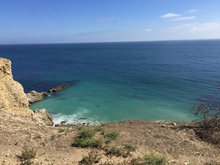 Vast Blue Ocean Meets Rugged Cliffs Under a Clear Sky Near the Shorelineの写真素材