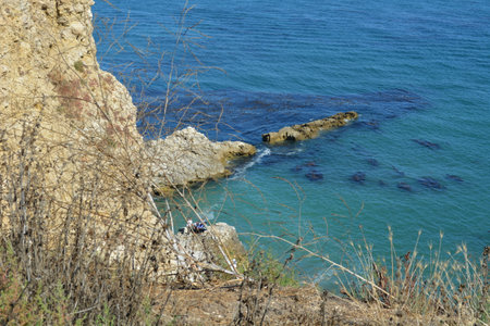 Scenic Coastal View With Rocky Shores and Calm Blue Waters Under a Clear Sky During Middayの写真素材