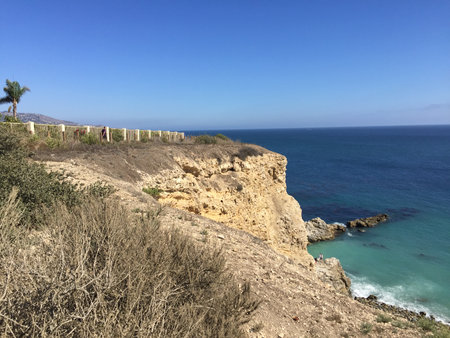 Witness Breathtaking Views From a Coastal Cliff With Turquoise Waters, Lush Vegetation, and a Clear Blue Sky in the Backgroundの写真素材
