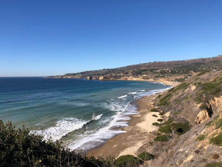 Serene Ocean View With Gentle Waves and Coastal Cliffs Under a Clear Blue Sky Near a Peaceful Beachの写真素材