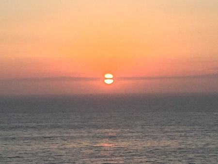 Vibrant Sunset Illuminates the Horizon Over a Calm Ocean, Creating a Serene Evening Atmosphereの写真素材