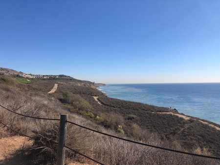 Coastal Trail Offers Stunning Views of Clear Blue Ocean and Rolling Hills at Sunny Middayの写真素材