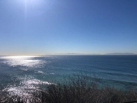 Ocean Waves Glisten Under the Bright Sun at a Tranquil Coastline During a Peaceful Morningの写真素材