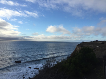 Breathtaking Coastal View at Sunset With Waves Crashing Against Cliffs and a Serene Skyの写真素材